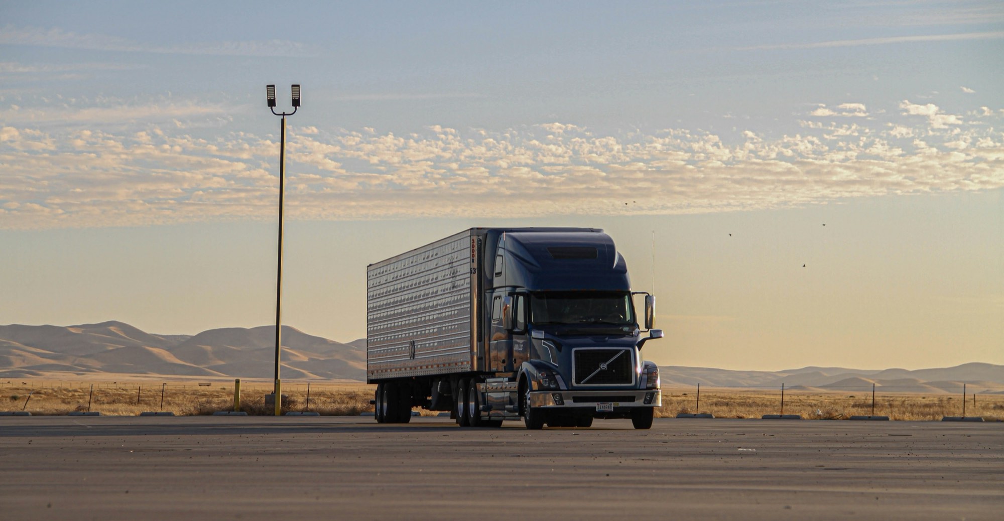 A freight truck parked under an open sky at golden hour
